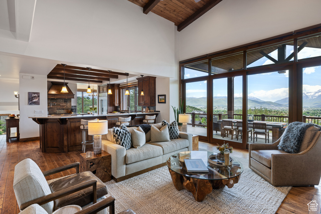 Living area featuring hardwood / wood-style floors, a mountain view, high vaulted ceiling, and wooden ceiling with exposed beams