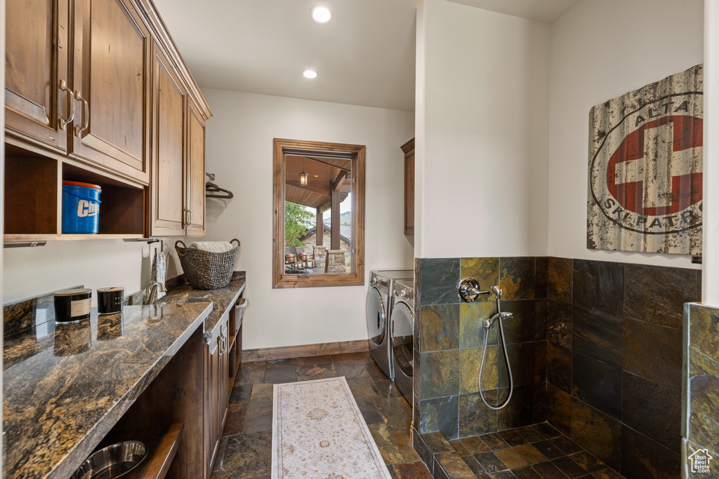 Laundry area featuring washing machine and dryer, stone tile floors, cabinet space, baseboards, and recessed lighting