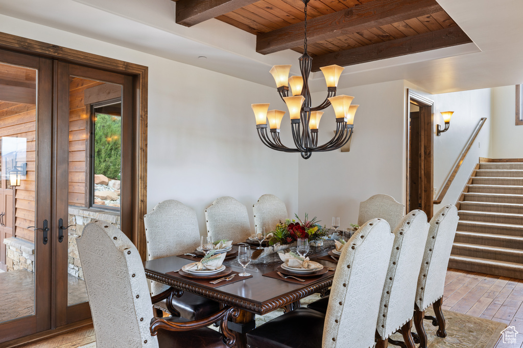 Dining area featuring french doors, a chandelier, wood ceiling with exposed beams, hardwood / wood-style flooring, and stairway