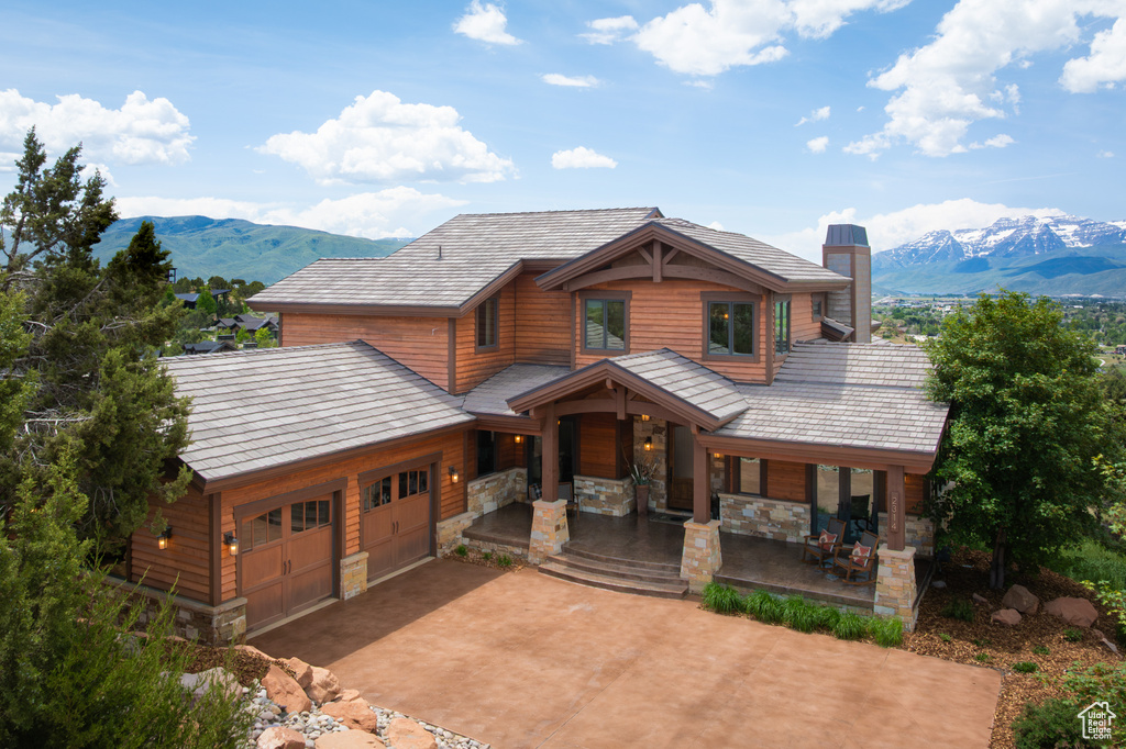Chalet / cabin featuring a mountain view, a chimney, driveway, a porch, and an attached garage