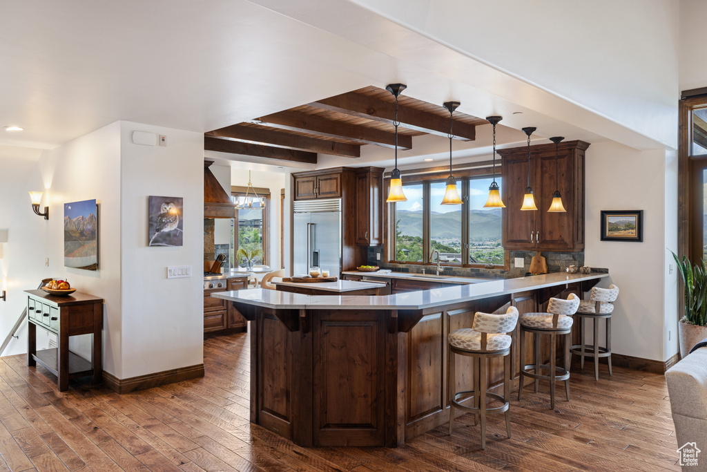 Kitchen featuring stainless steel built in refrigerator, healthy amount of natural light, a kitchen bar, a peninsula, and beam ceiling