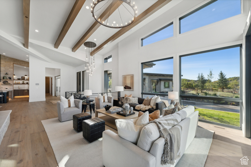 Living room featuring a chandelier, a high ceiling, beam ceiling, wood finished floors, and recessed lighting