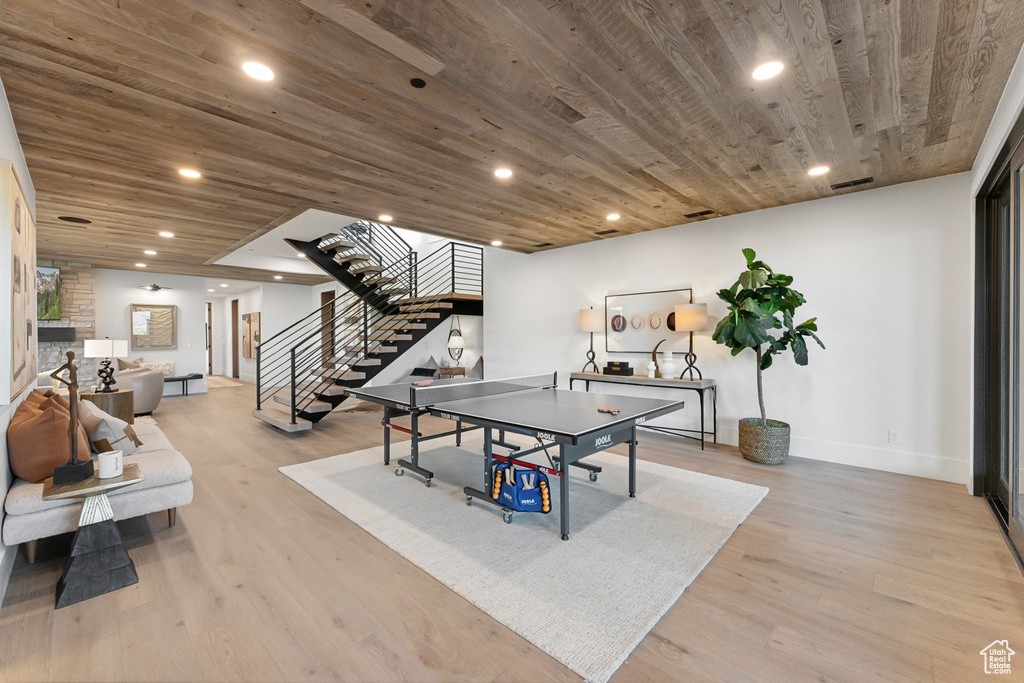 Playroom featuring light wood-style floors, wooden ceiling, baseboards, recessed lighting, and a stone fireplace