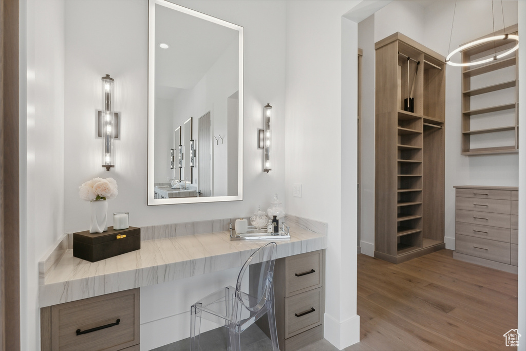 Full bath with wood finished floors, vanity, a spacious closet, and baseboards