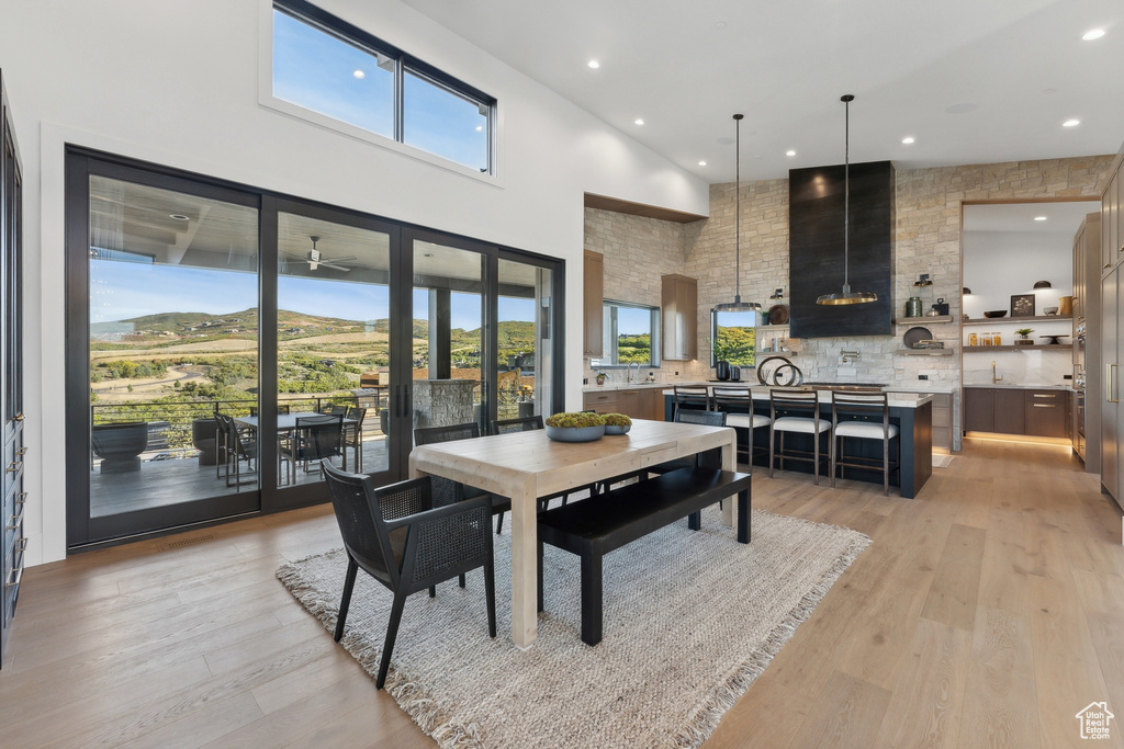 Dining area featuring light wood-style floors, a high ceiling, recessed lighting, and ceiling fan
