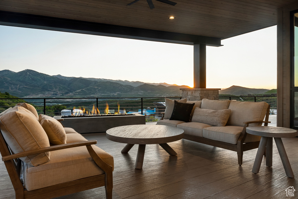 Patio terrace at dusk with a mountain view, ceiling fan, and a balcony