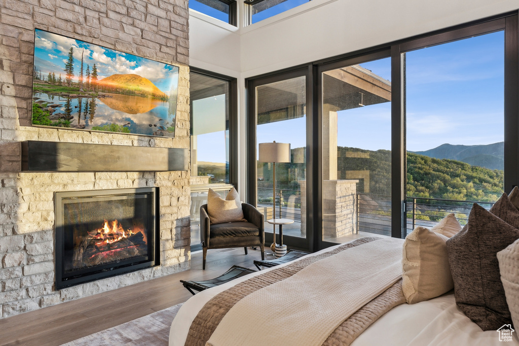 Bedroom featuring wood finished floors, a fireplace, a mountain view, and access to outside