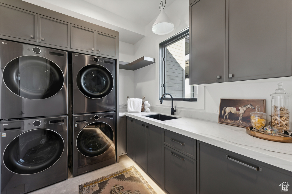Washroom featuring stacked washer and clothes dryer, cabinet space, and separate washer and dryer