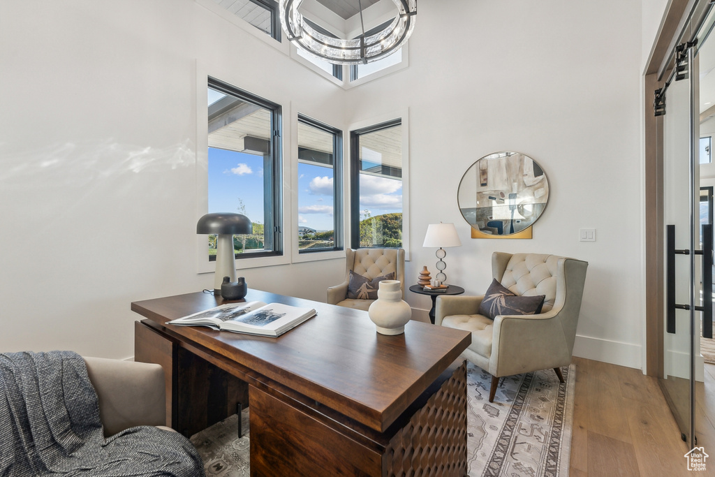 Home office with healthy amount of natural light, light wood-style floors, baseboards, and a towering ceiling