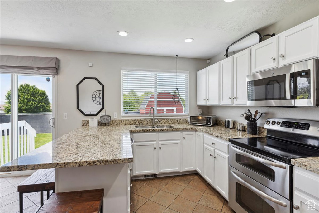 Kitchen with stainless steel appliances, a sink, a peninsula, a kitchen bar, and white cabinetry