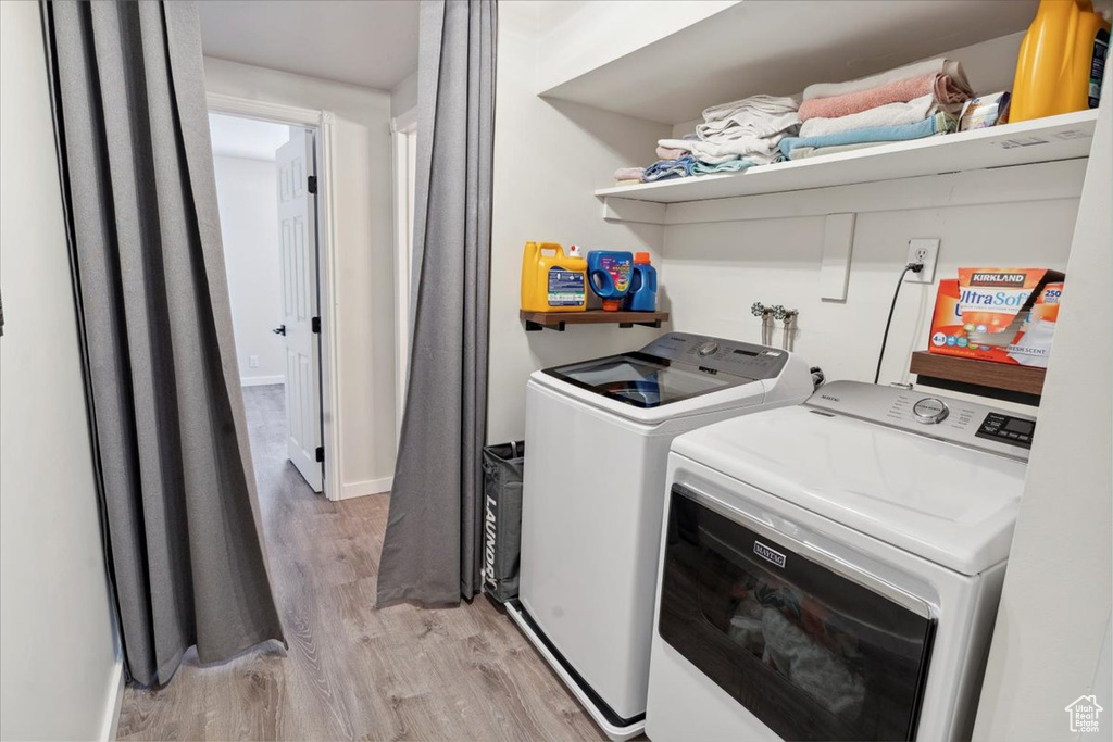 Laundry area featuring washer and clothes dryer, light wood-style flooring, and baseboards