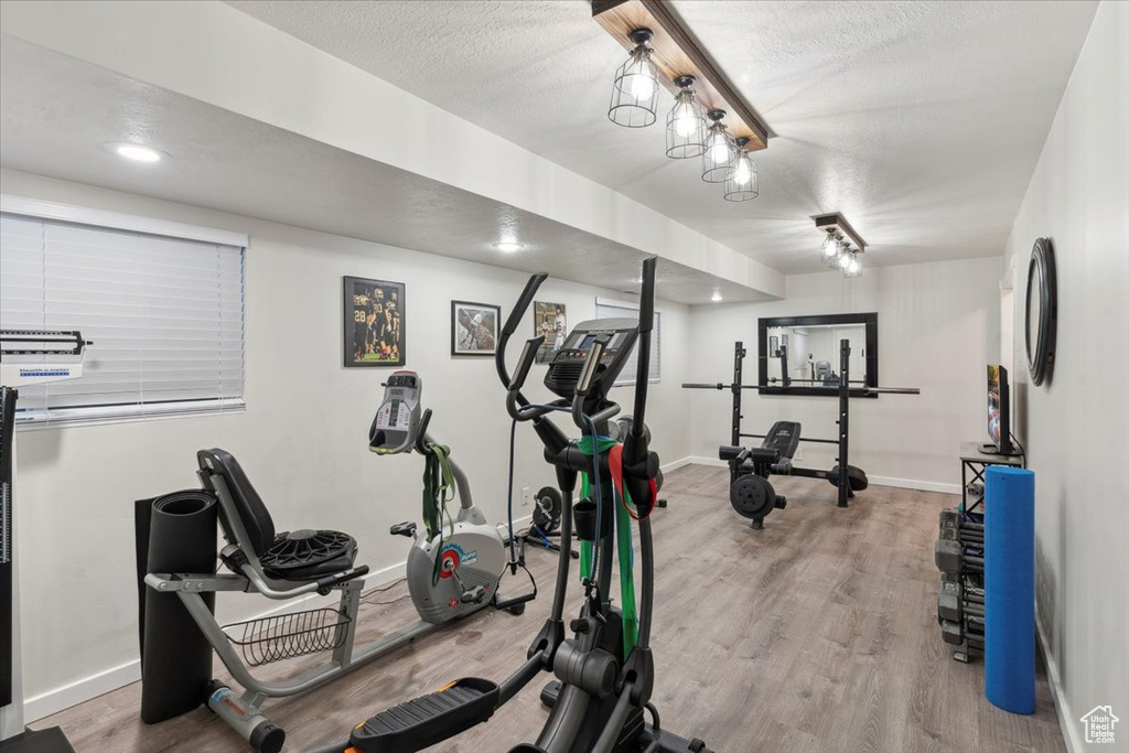 Workout room with wood finished floors, baseboards, and a textured ceiling