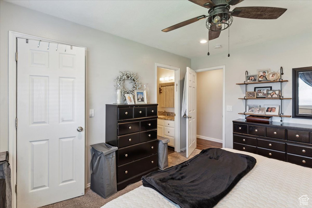 Carpeted bedroom with baseboards, ensuite bathroom, and ceiling fan