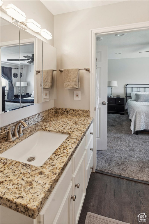 Bathroom featuring connected bathroom, vanity, wood finished floors, and ceiling fan