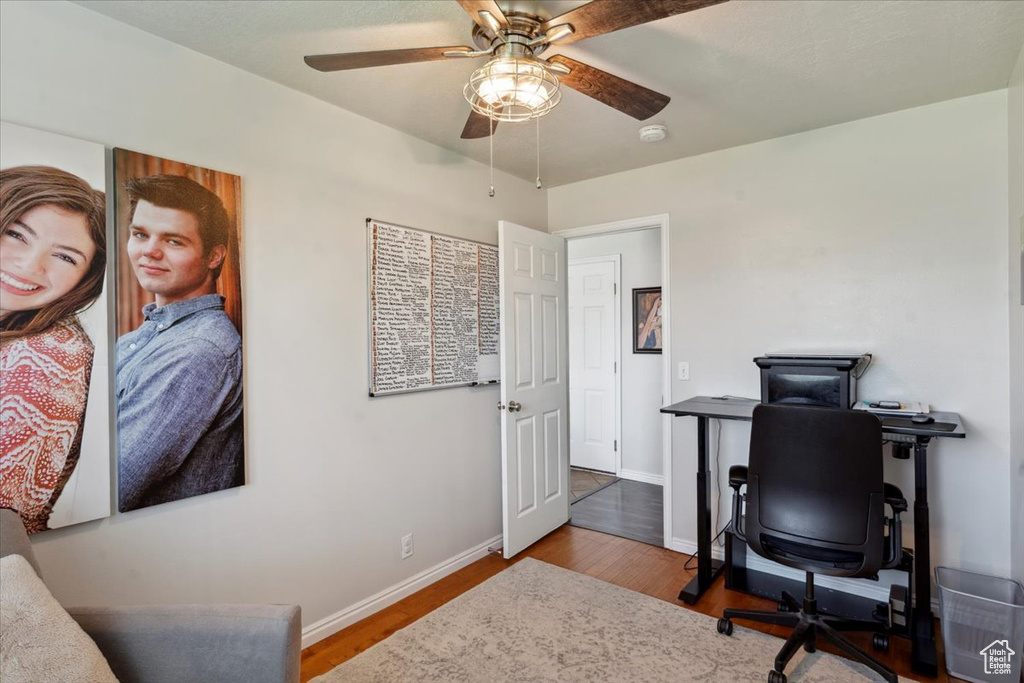 Office space with a ceiling fan, wood finished floors, and baseboards