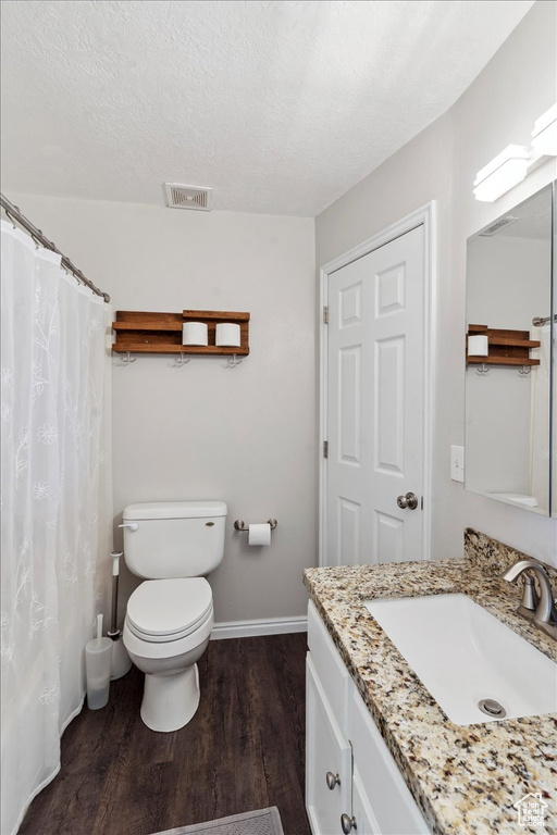 Full bath featuring vanity, wood finished floors, toilet, baseboards, and a textured ceiling