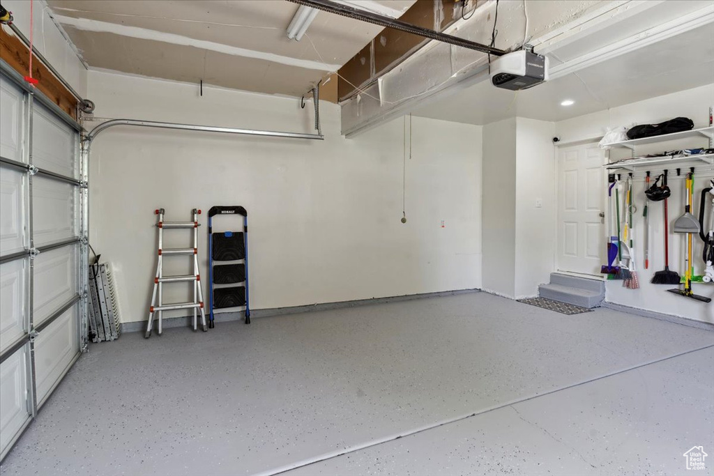 Garage featuring a garage door opener and baseboards