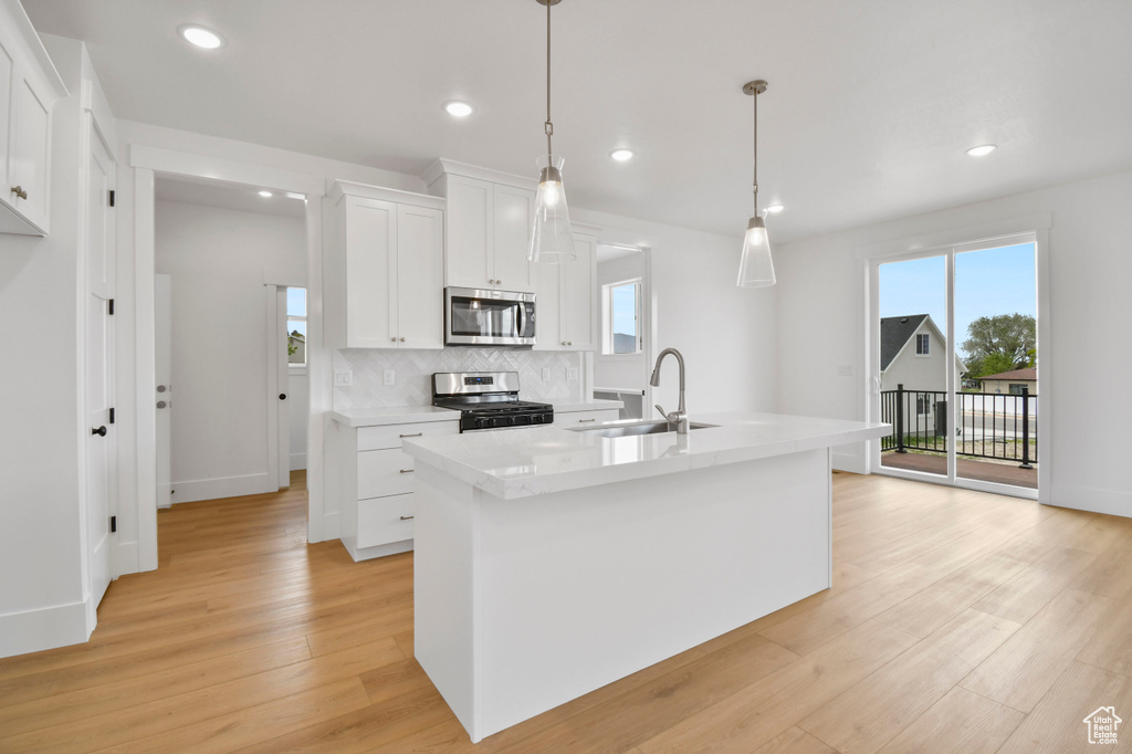 Kitchen featuring appliances with stainless steel finishes, a sink, healthy amount of natural light, light wood-style flooring, and recessed lighting