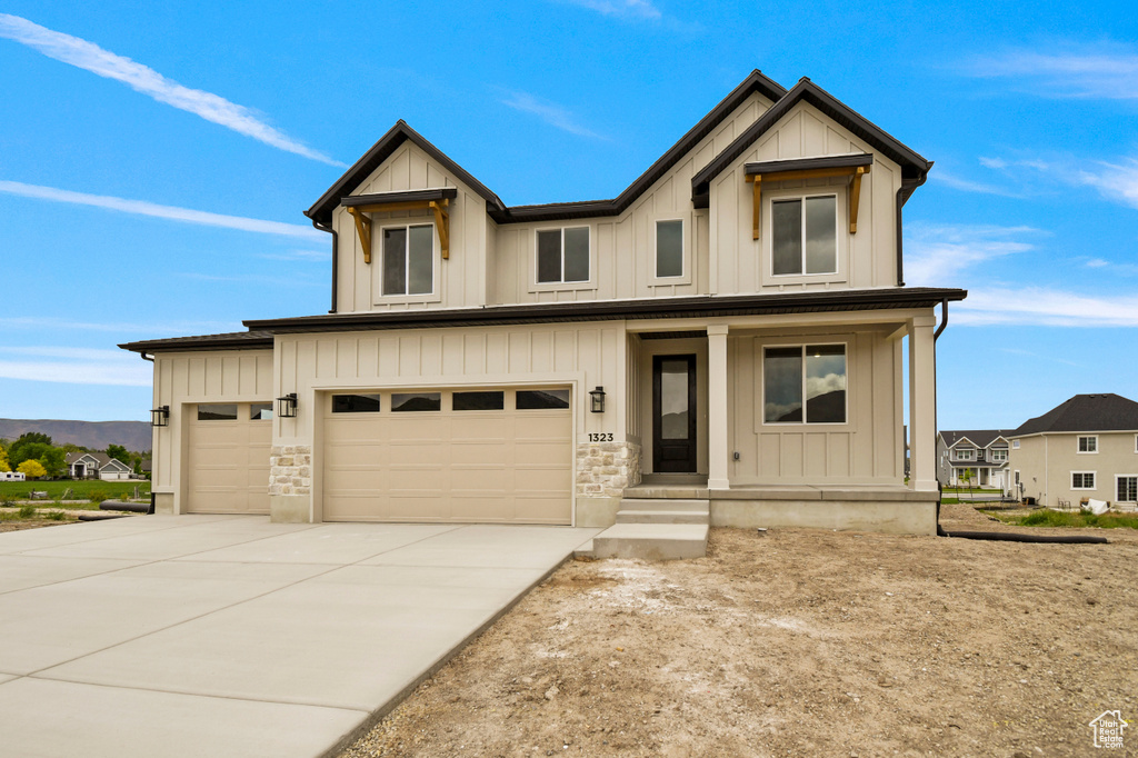 View of front of house featuring covered porch, concrete driveway, board and batten siding, and a garage