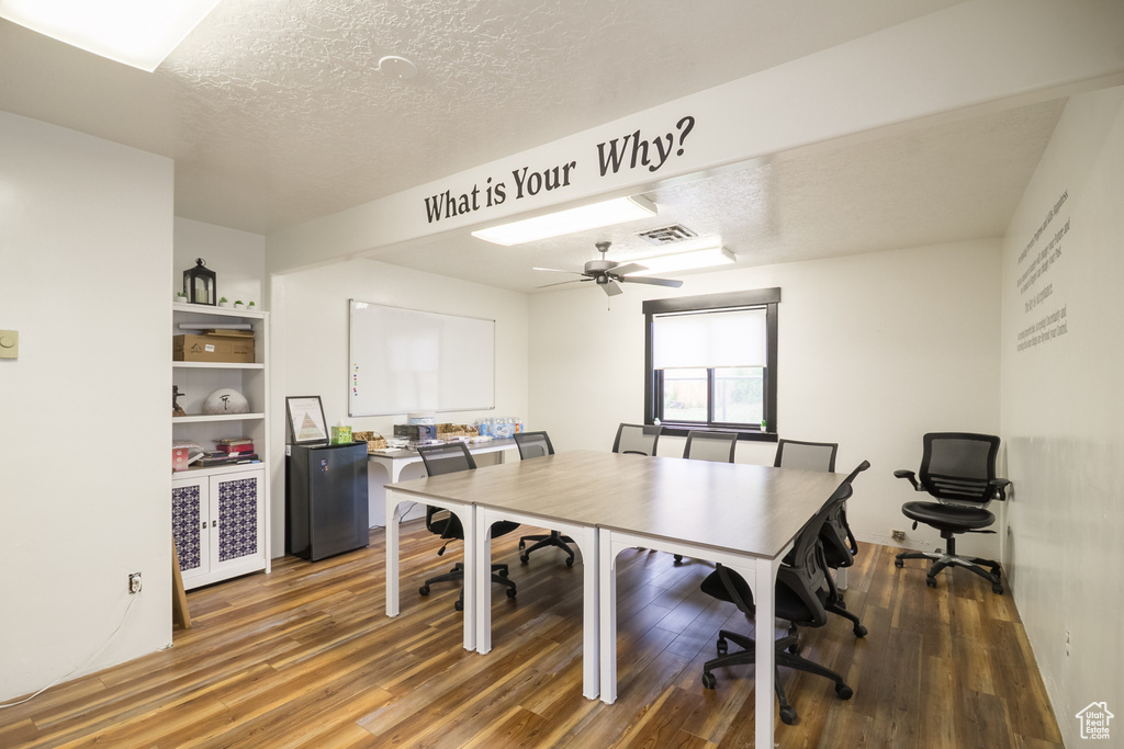 Home office featuring light wood finished floors, ceiling fan, and a textured ceiling