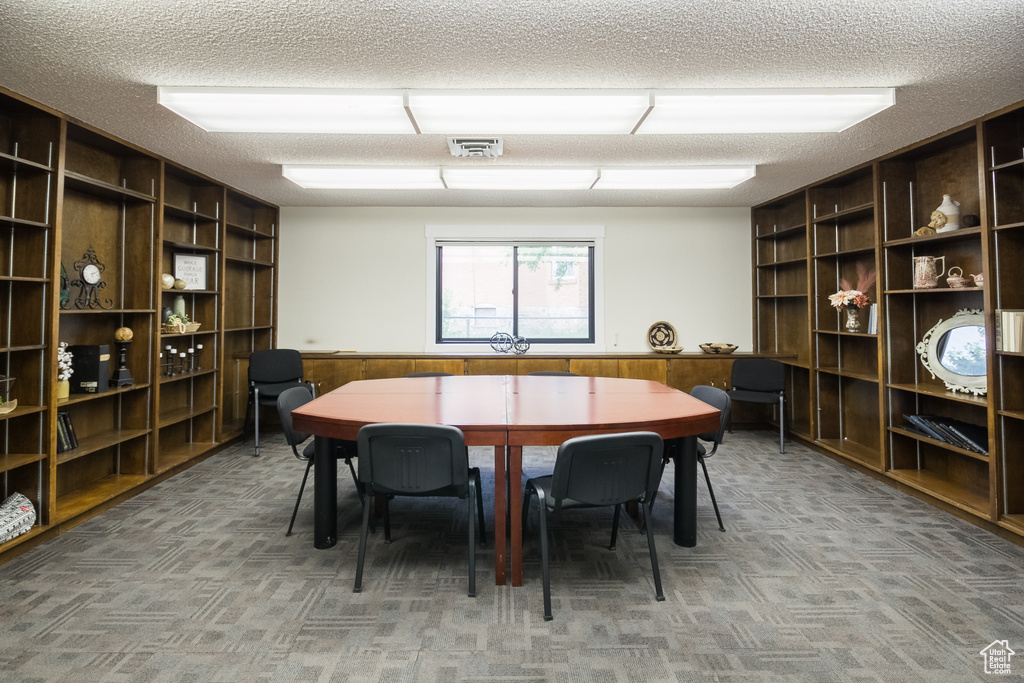 Dining space featuring a textured ceiling, wooden walls, built in features, carpet flooring, and a wainscoted wall