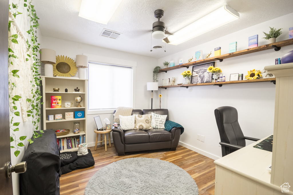 Home office with a ceiling fan, wood finished floors, and baseboards