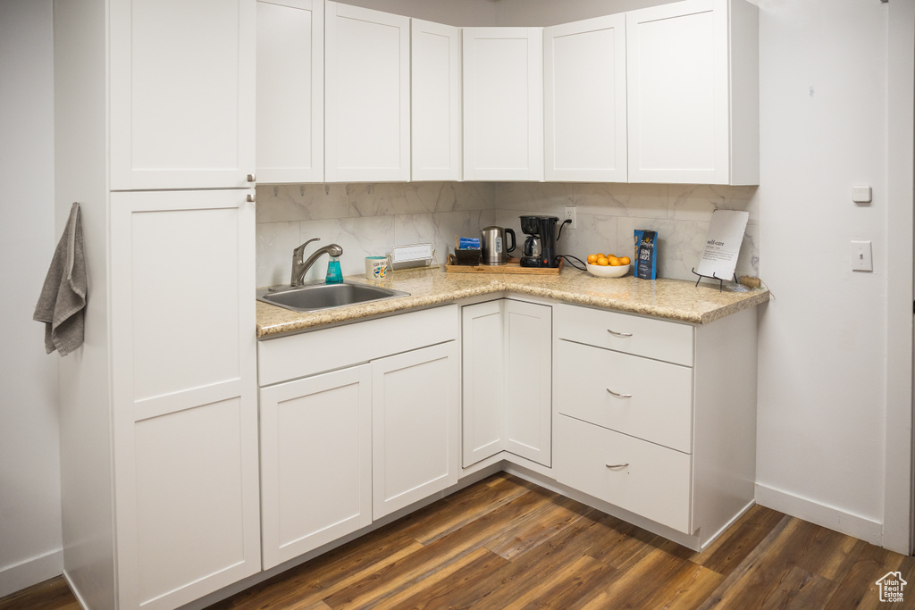 Kitchen featuring a sink, light countertops, dark wood-type flooring, baseboards, and white cabinetry