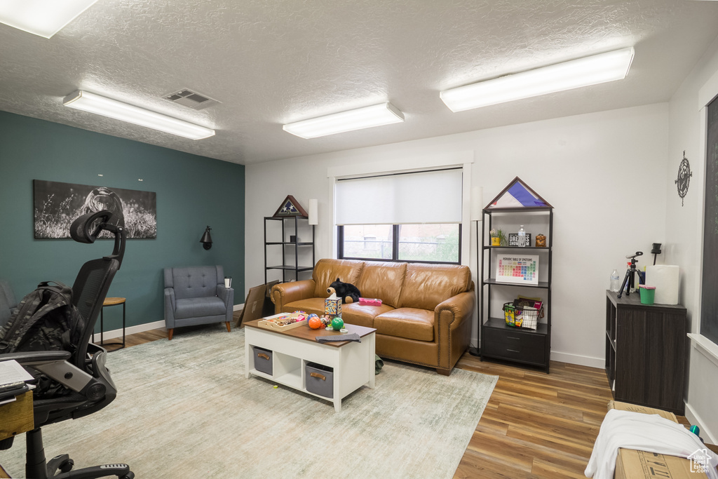 Home office with a textured ceiling, wood finished floors, and baseboards