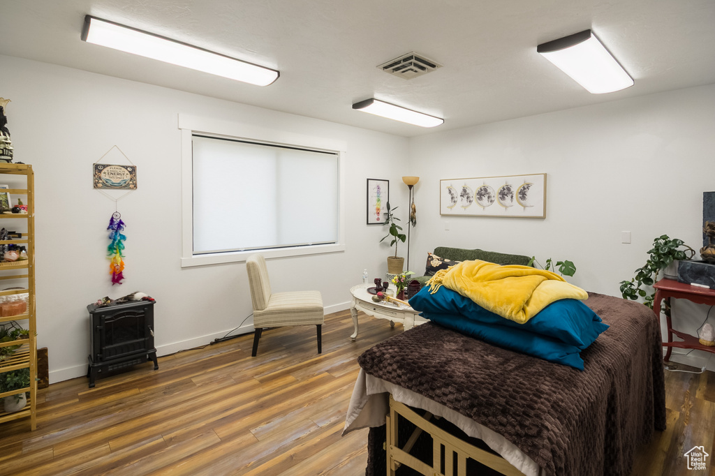 Bedroom with a wood stove, wood finished floors, and baseboards