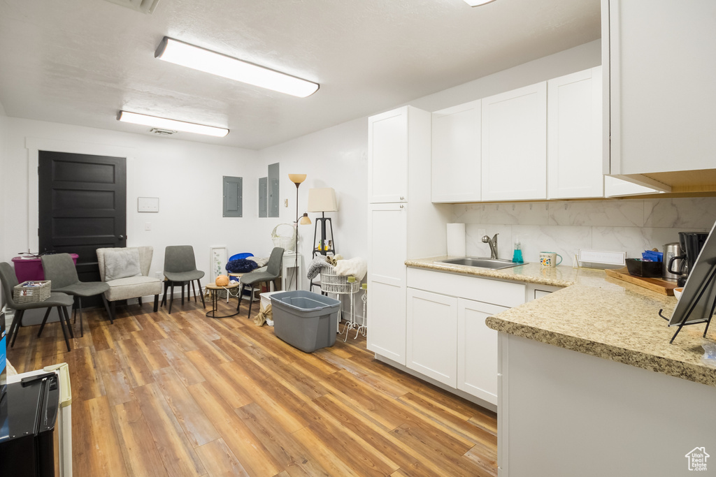 Kitchen featuring a sink, white cabinets, light wood finished floors, and tasteful backsplash