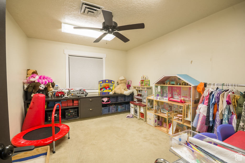 Game room with carpet flooring, ceiling fan, and a textured ceiling