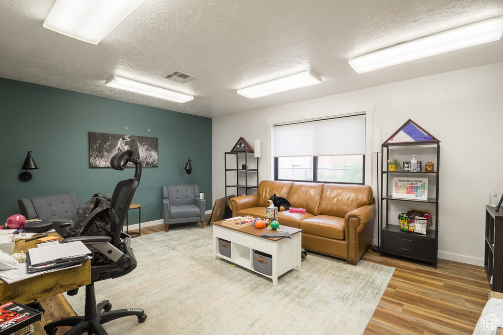 Office area with a textured ceiling, light wood-type flooring, and baseboards