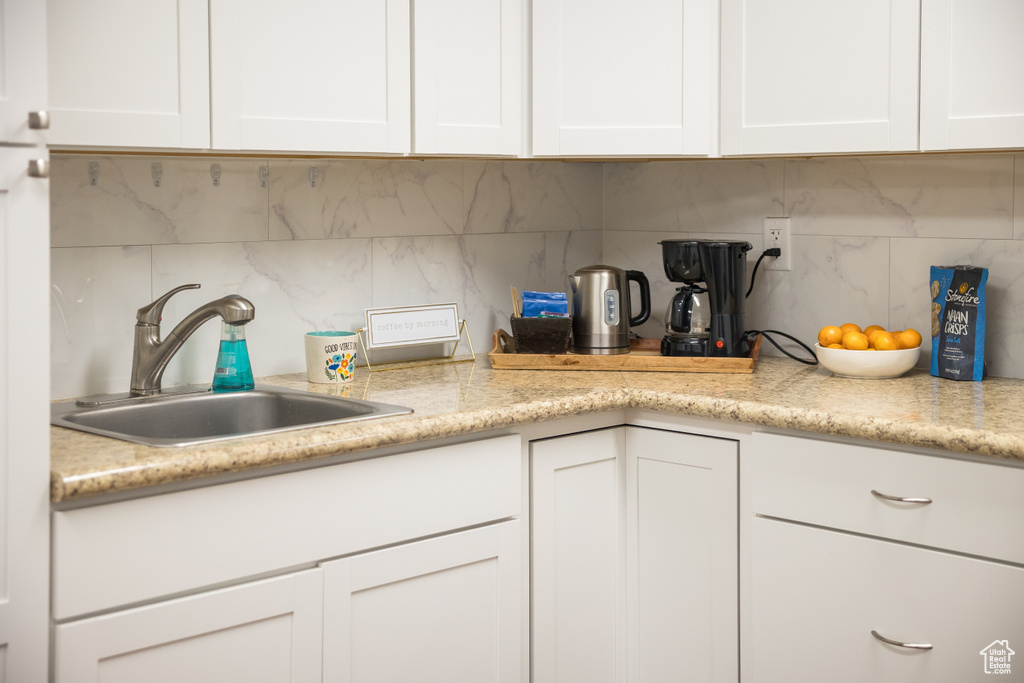 Kitchen featuring a sink, backsplash, and light countertops