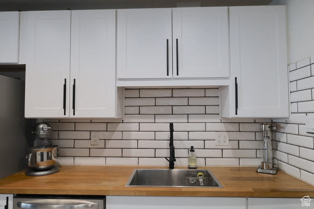 Kitchen with wood counters, decorative backsplash, and white cabinets