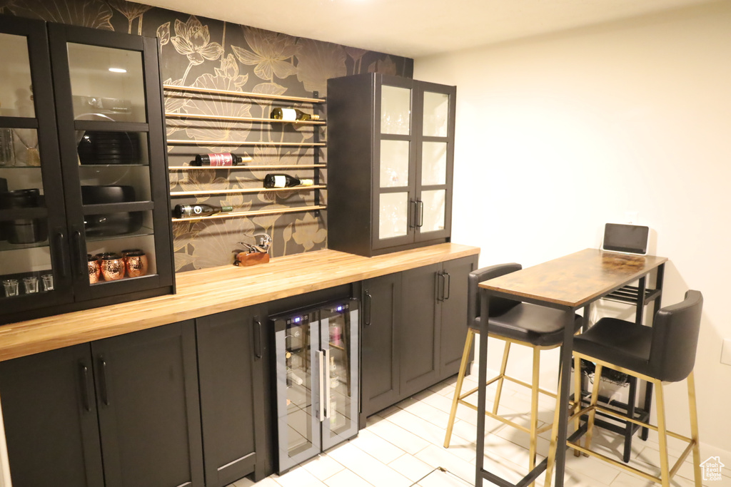Indoor dry bar with wallpapered walls, wine cooler, and an accent wall