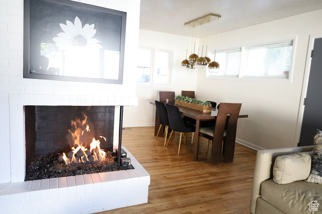 Dining area featuring wood finished floors, a brick fireplace, and baseboards