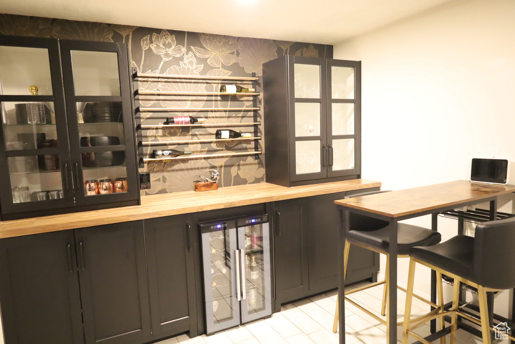 Indoor dry bar featuring beverage cooler and wallpapered walls