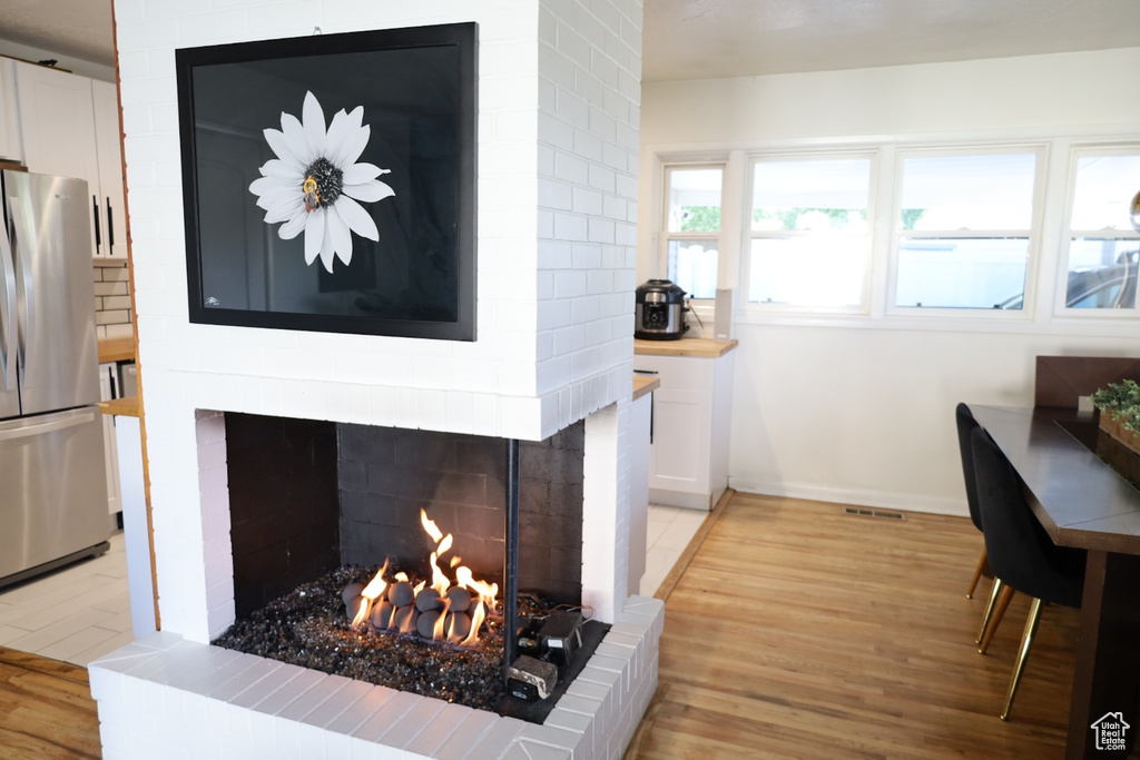 Dining space featuring a fireplace, light wood finished floors, and baseboards