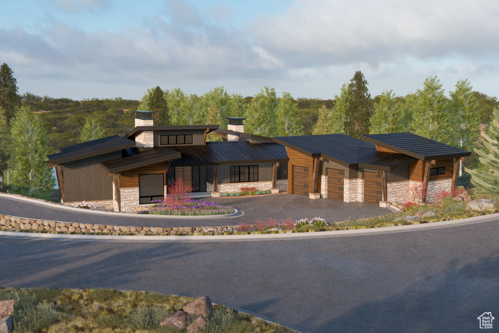 View of building exterior featuring an attached garage, asphalt driveway, and a forest view