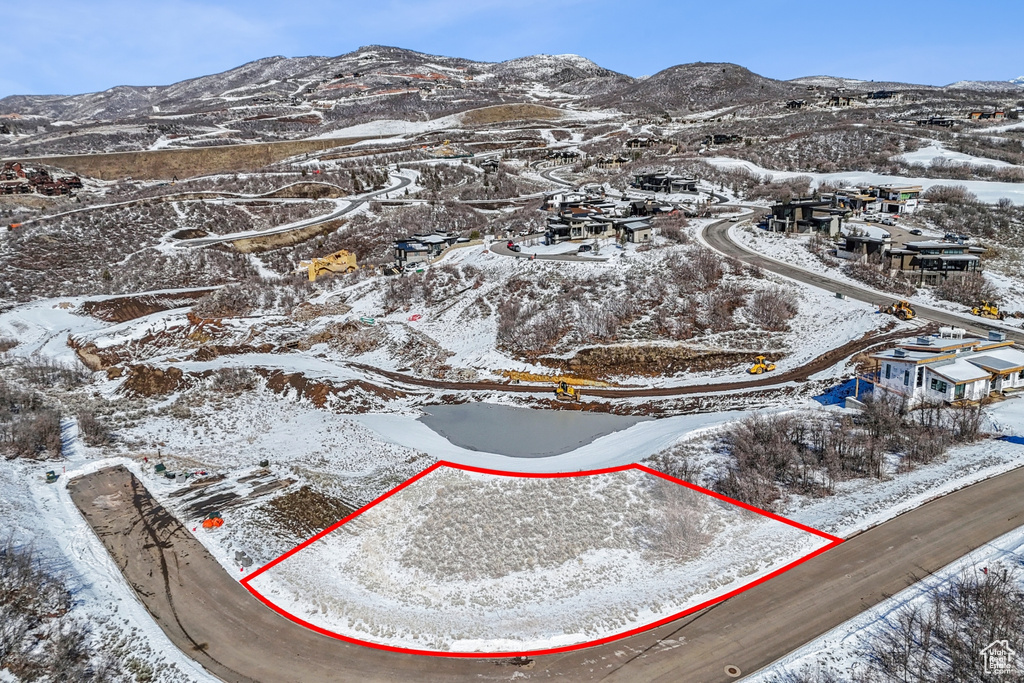 Snowy aerial view featuring property parcel outlined and a mountain view
