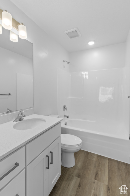 Full bathroom with vanity, wood finished floors, toilet, and shower / bathtub combination