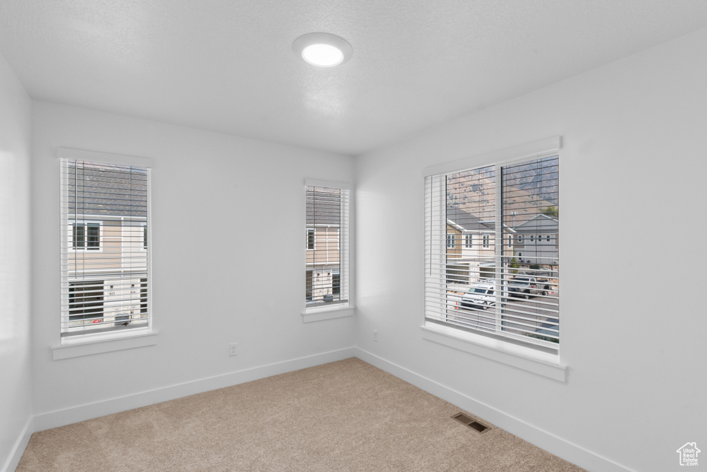 Spare room featuring light carpet and baseboards