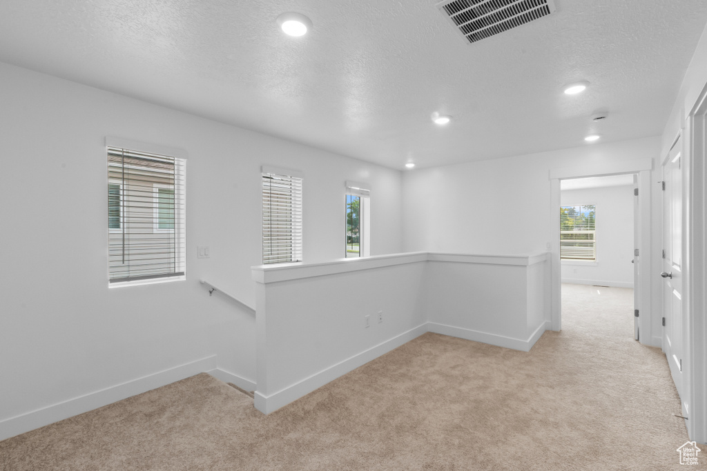 Carpeted spare room with plenty of natural light, baseboards, a textured ceiling, and recessed lighting