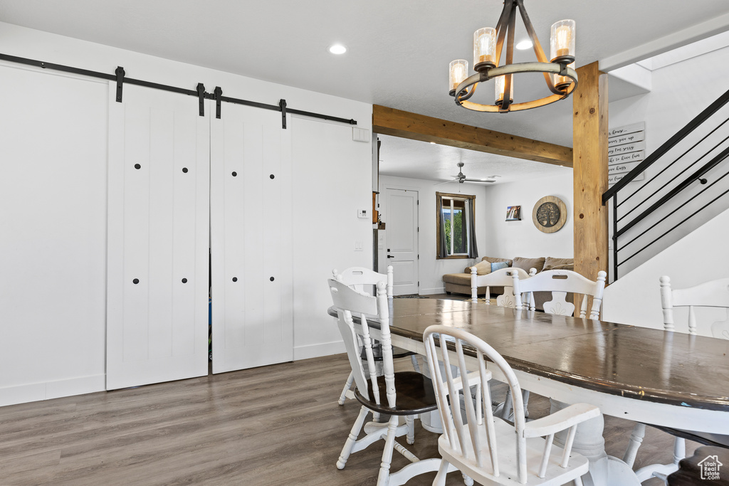 Dining area with a barn door, a chandelier, wood finished floors, recessed lighting, and stairway
