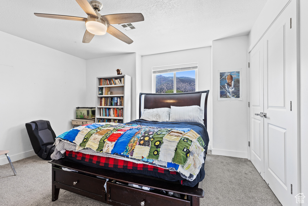 Bedroom with carpet, baseboards, ceiling fan, a textured ceiling, and a closet