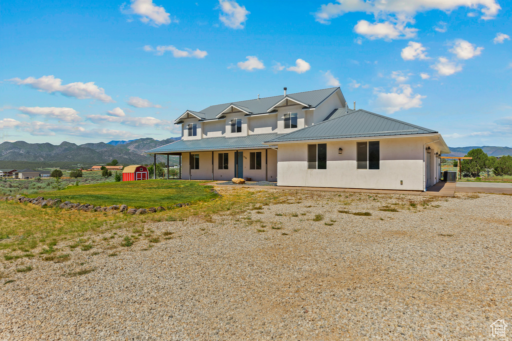 View of front of home featuring a mountain view, a porch, metal roof, and a front lawn