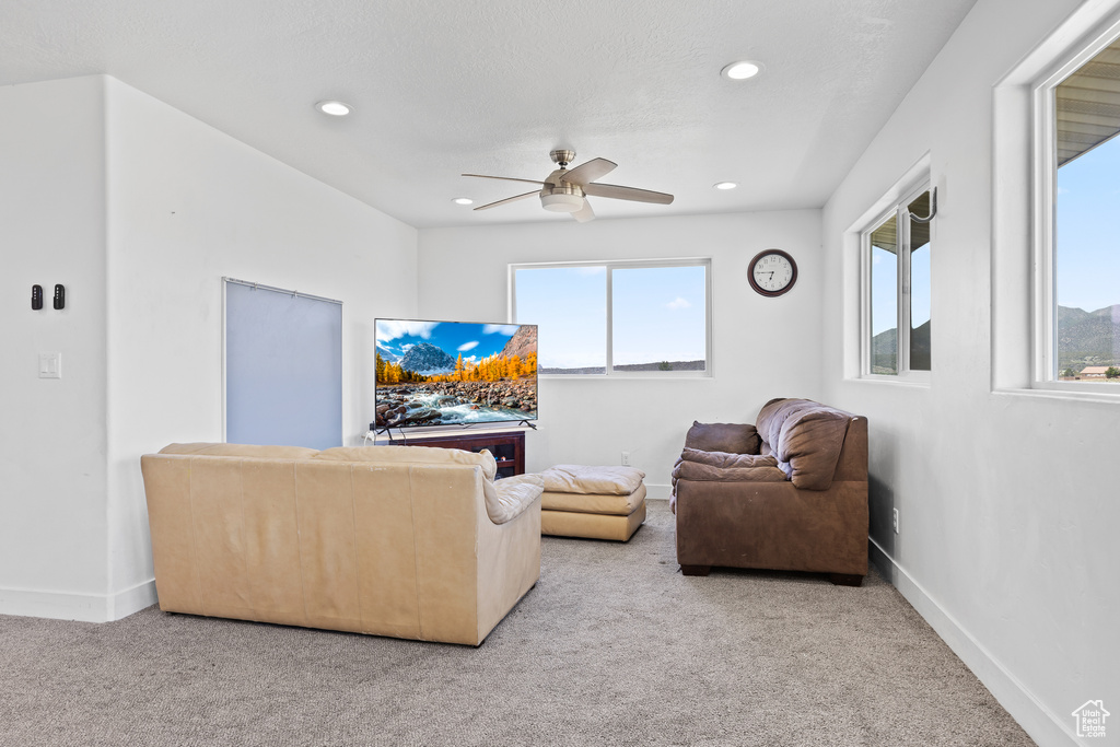Carpeted living room featuring a ceiling fan, baseboards, and recessed lighting