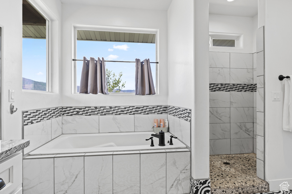 Full bathroom with a garden tub, plenty of natural light, tiled shower, and vanity