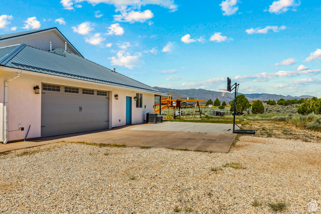 View of home\'s exterior featuring a mountain view, stucco siding, a standing seam roof, metal roof, and central AC unit