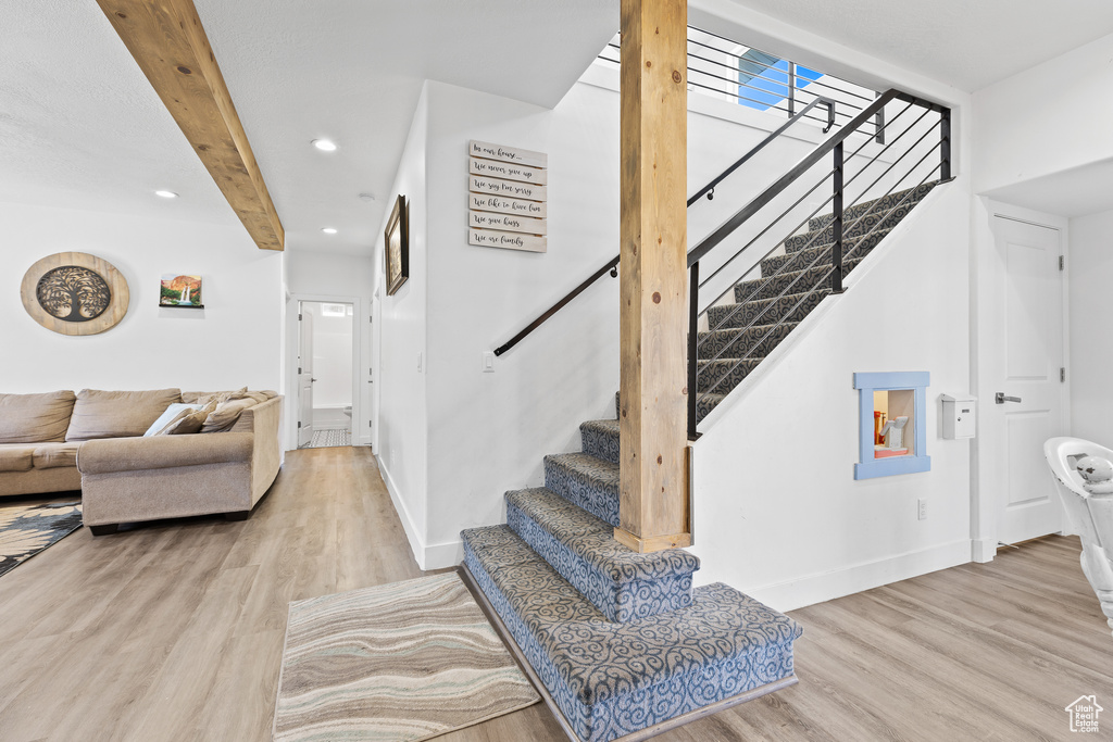 Stairway featuring wood finished floors, recessed lighting, baseboards, and beam ceiling